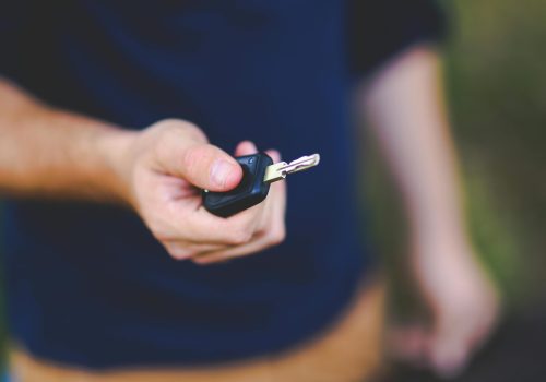 A hand holding a car key outdoors, emphasizing security and control.